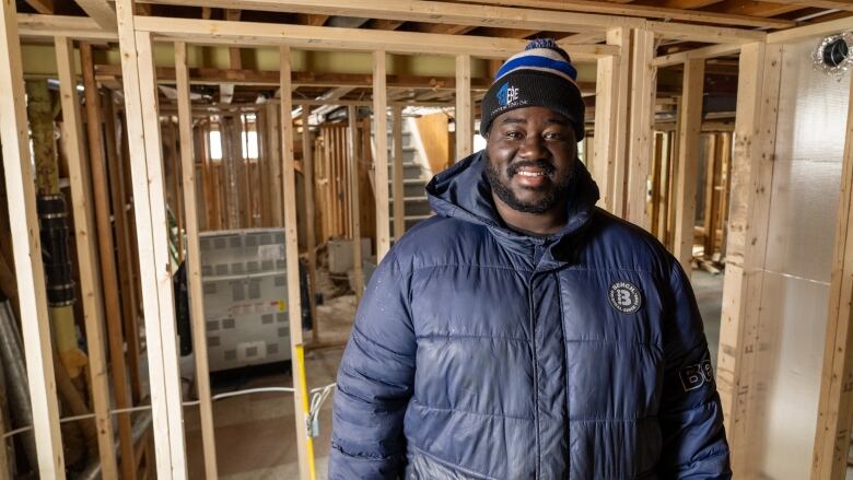 a man stands in a half finished basement 