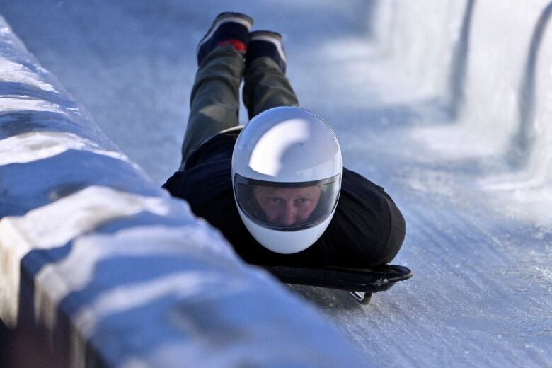 A person rides a skeleton sled down a track.