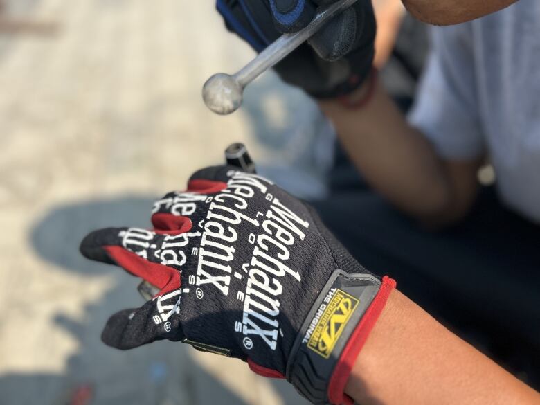 A hand wearing a biking glove holds a lighter to a drug pipe.