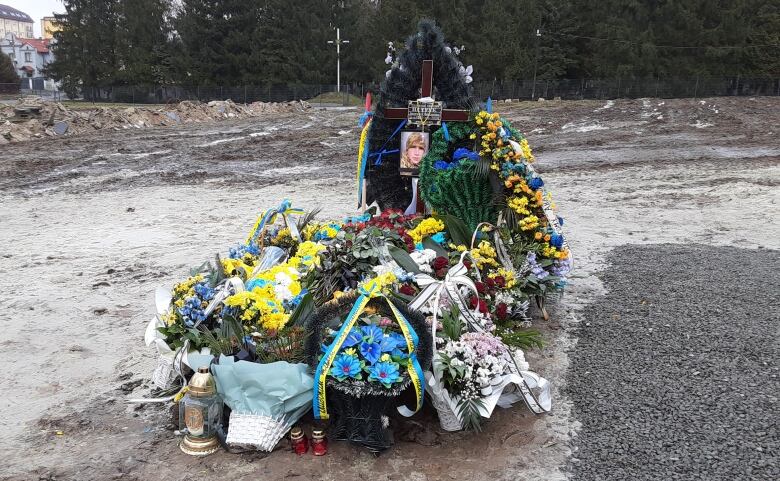 A memorial to a soldier with his photo and lots of blue and yellow flowers around it. 