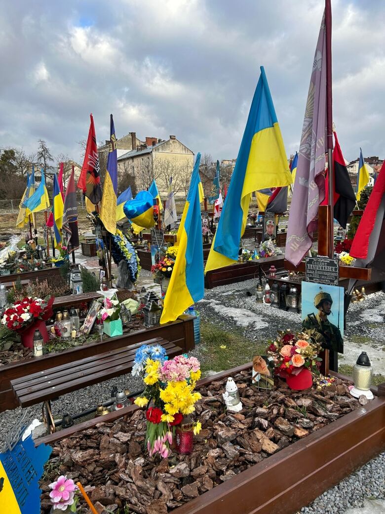 A grave yard filled with Ukraine flags and photos of dead soldiers 