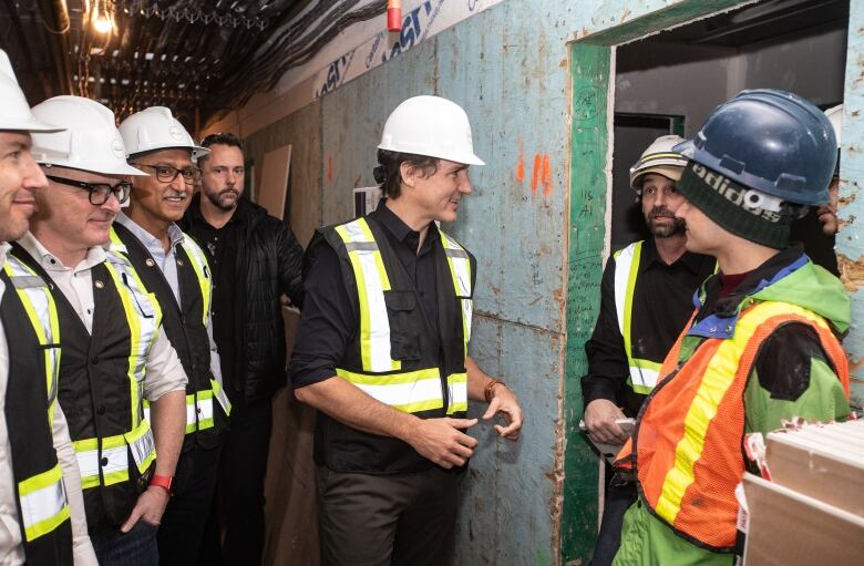 Seven men wearing black and white hard hats.