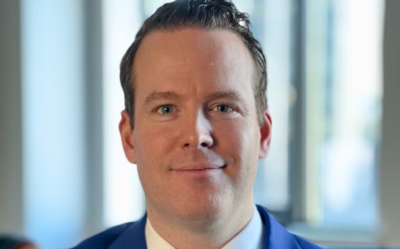 A man in a blue suit smiles for the camera.