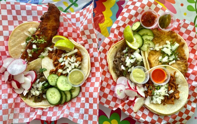 Two plates of three different open-face tacos sprinkled with slices of cucumber, radishes and diced onion. They are accompanied by slices of lime and little cups of salsas.