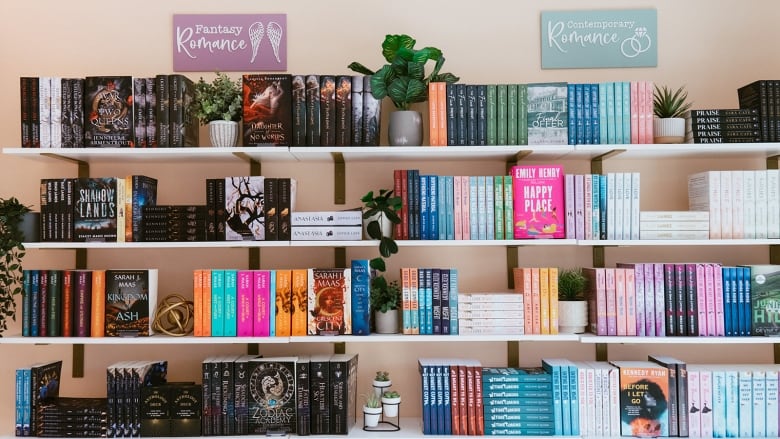 Book titles are shown on shelves in a book store. A sign that reads 