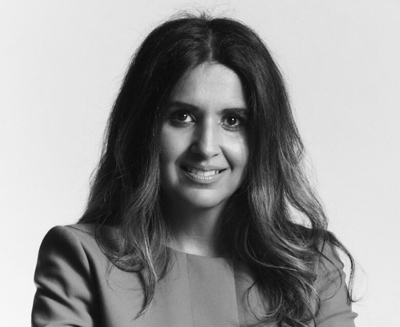 A black and white portrait of a female lawyer posing with her hands folded. 