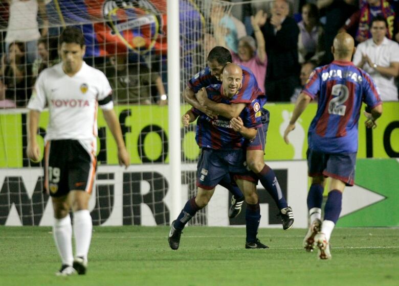 Soccer platers celebrate on a field.