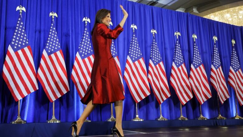 Haley waves on stage, with US flags behind her