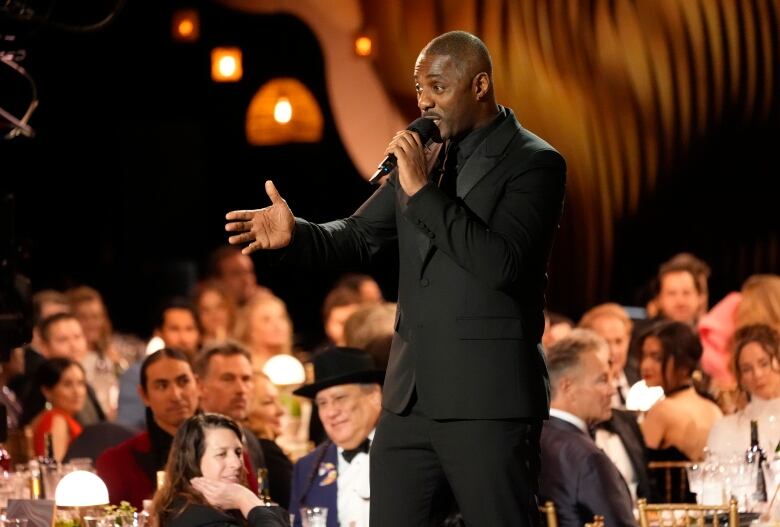 Actor Idris Elba hold a microphone. 