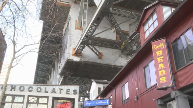 A building in the shadow of a bridge overhead.