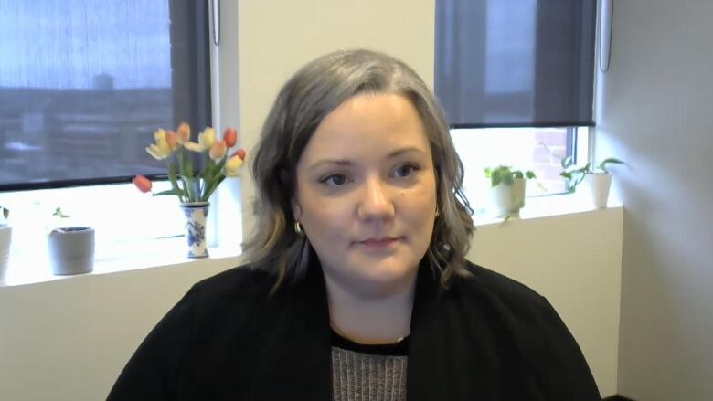 A woman in an office looks toward a camera.