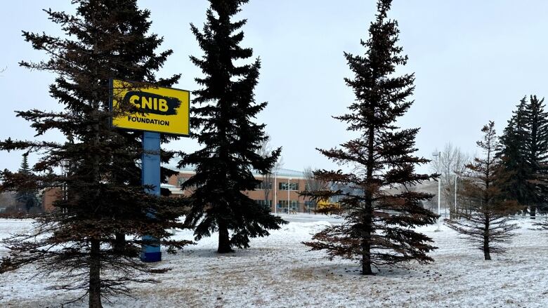 A sign on a snowy slope surrounded by trees. 