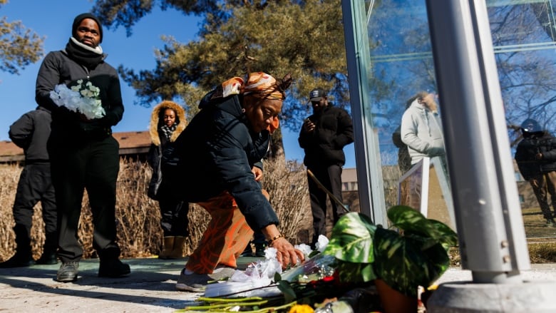 A person lays flowers at a bus stop.