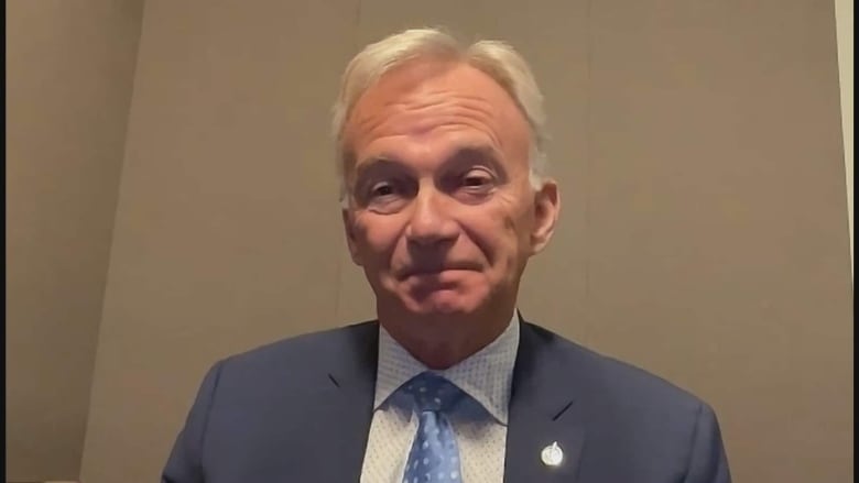 A man in a suit in front of a plain background