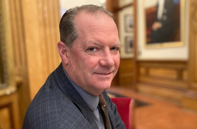 A grinning man wearing a blazer 