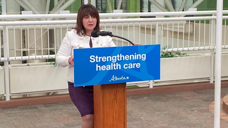 A woman in a business suit stands at a podium.