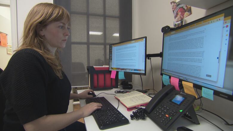 A woman is shown working at a desktop computer.