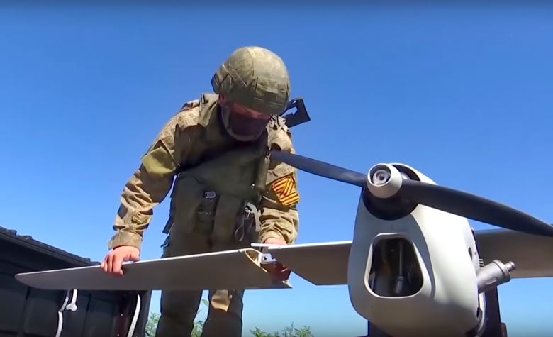 A soldier adjusts the wing of a drone