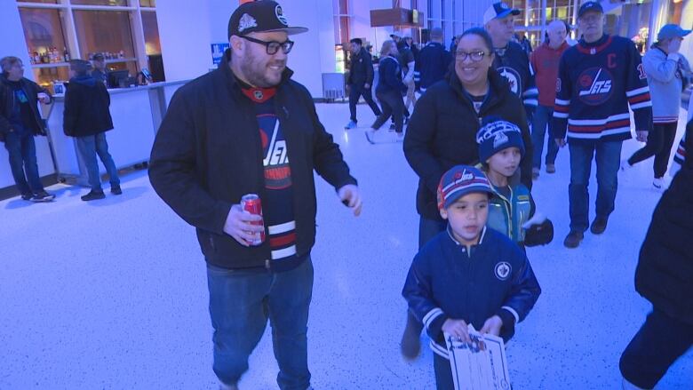 A dad, mom and their two young sons are pictured in Winnipeg Jets clothing in the concourse of the National Hockey League team's home arena.