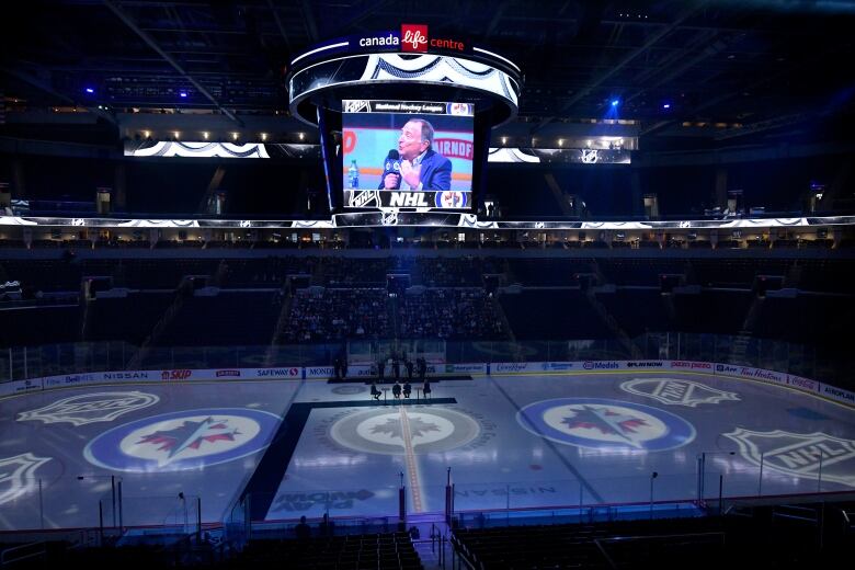 NHL commissioner Gary Bettman is pictured on the jumbotron above the ice surface in a darkened hockey arena.