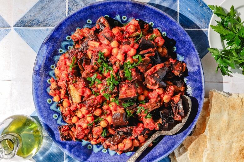 Overhead shot of Lebanese moussaka on a bright blue plate, on a blue and white tiled surface.  