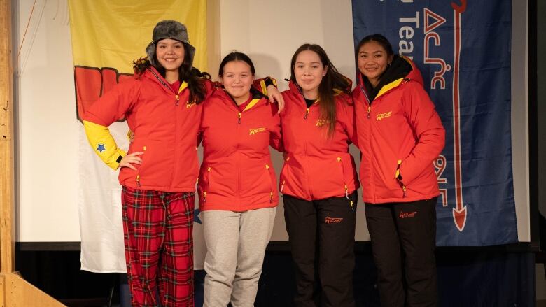 Four girls pose in red and yellow jackets. 