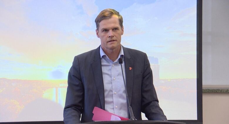 A man stands behind a podium speaking into a microphone. 