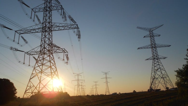 Power transmission lines with the sun setting behind them.