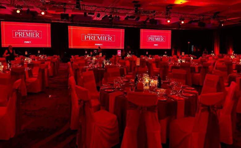 A conference hall full of tables with screens that read the words 