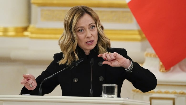 A woman with hands raised stands behind a podium