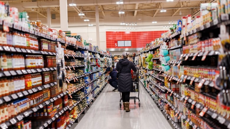 Shoppers are seen in the aisle of a grocery store. 