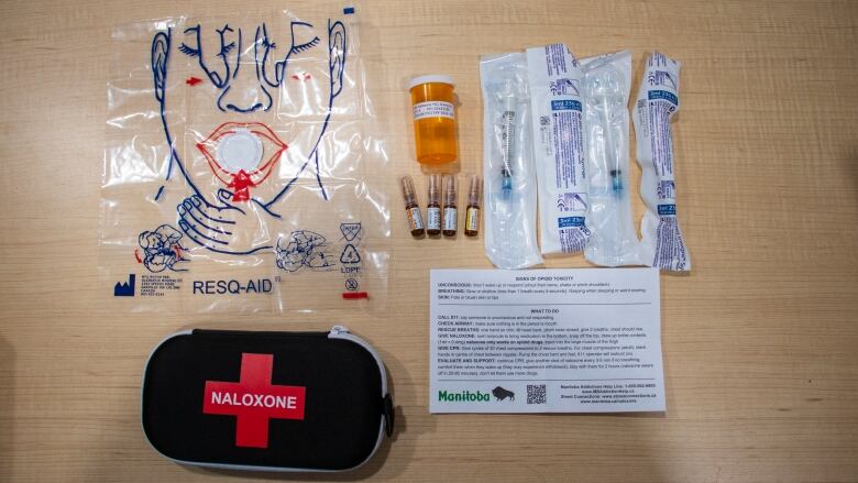 Items from a naloxone kit sit on a desk.