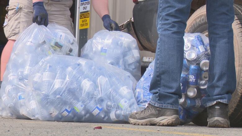 Several garbage bags are pictured full of water bottles and beer cans.