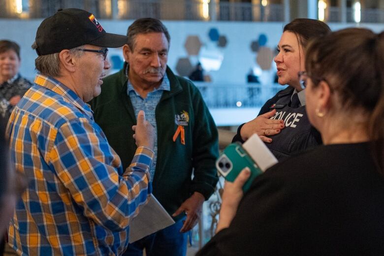 A man in a plaid shirt speaks with a police officer