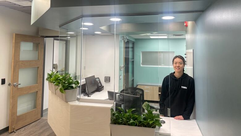 A young woman stands at a reception desk in a brightly lit health centre