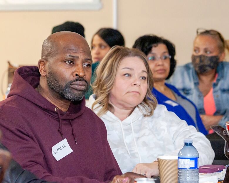 A Black man and a white woman listen during a community meeting about the land trust. 