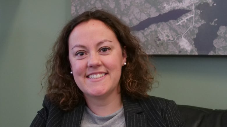 A portrait of a smiling woman in front of a green wall.