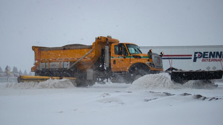 A snow plow clears snow on a highway.