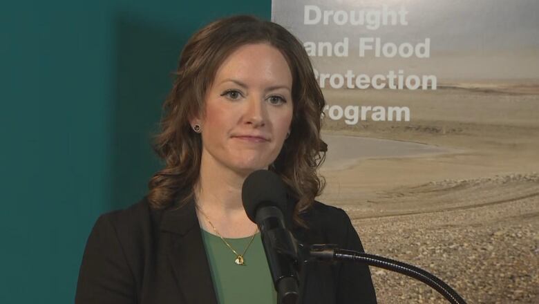 A woman speaks behind a microphone.