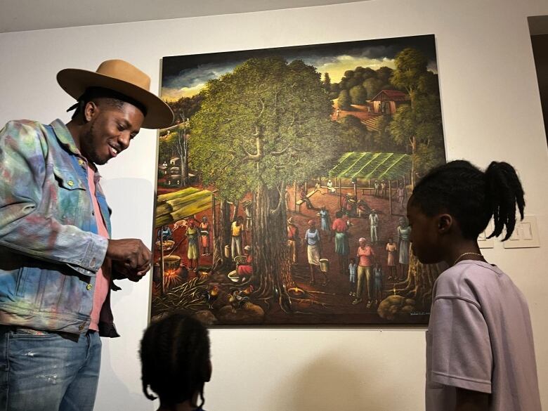 A man stands in a front of a painting with two children.