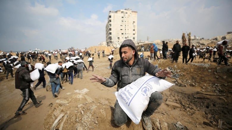 FILE PHOTO: Palestinians carry bags of flour they grabbed from an aid truck near an Israeli checkpoint, as Gaza residents face crisis levels of hunger, amid the ongoing conflict between Israel and Hamas, in Gaza City, February 19, 2024.