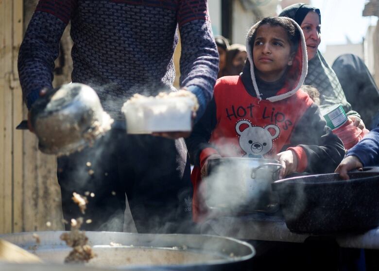 Palestinian children wait to receive food cooked by a charity kitchen amid shortages of food supplies, as the ongoing conflict between Israel and the Palestinian Islamist group Hamas continues, in Rafah, in the southern Gaza Strip, March 5, 2024.