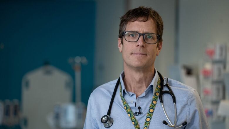 A male medical oncologist wearing a blue shirt, lanyard and stethoscope. 