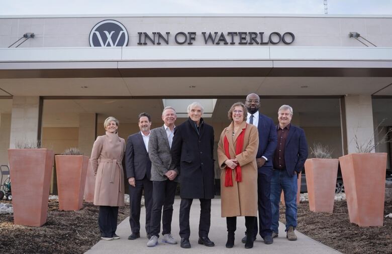 Photo of people standing in front of a building with the sign 