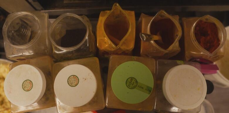 An image of several large spice containers in a South Asian restaurant kitchen.