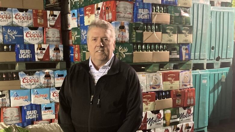 David McCarthy poses for a photo in front of a wall of bottles