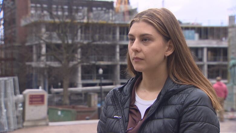 A woman stands in front of a construction site.