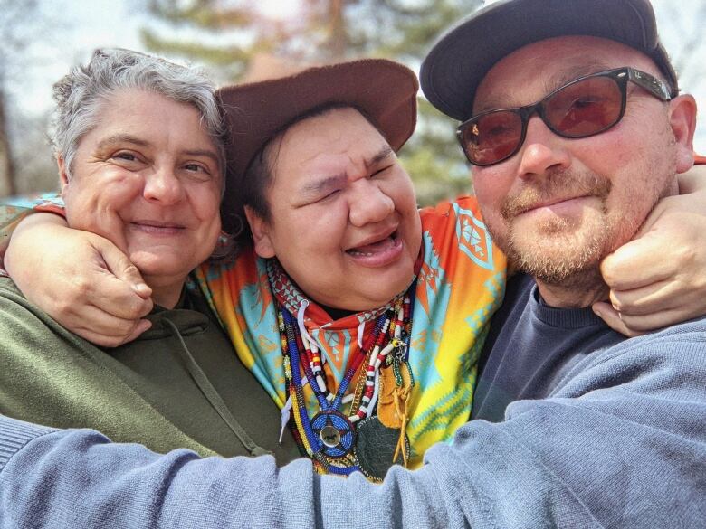 A family of three smile in a photo. 