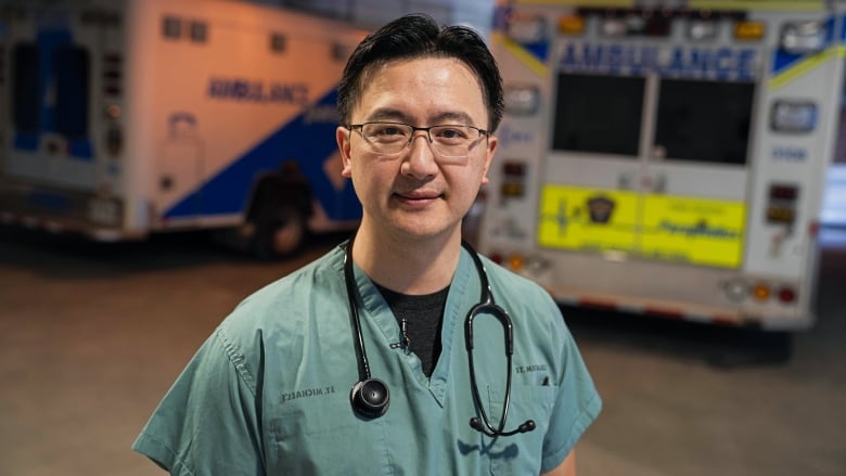 Dr. Steve Lin, the interim chief of emergency medicine at Unity Health Toronto's St. Michael's Hospital, stands between two ambulances.