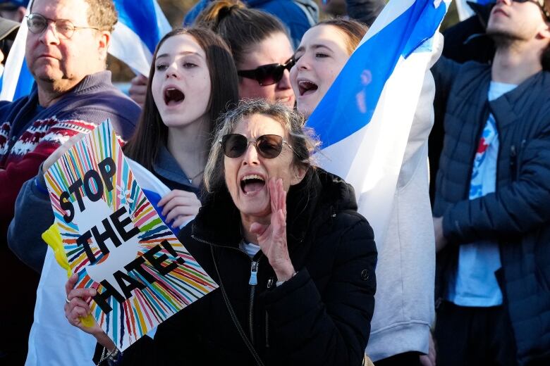 Protesters at an event. One of them holds a sign that says 